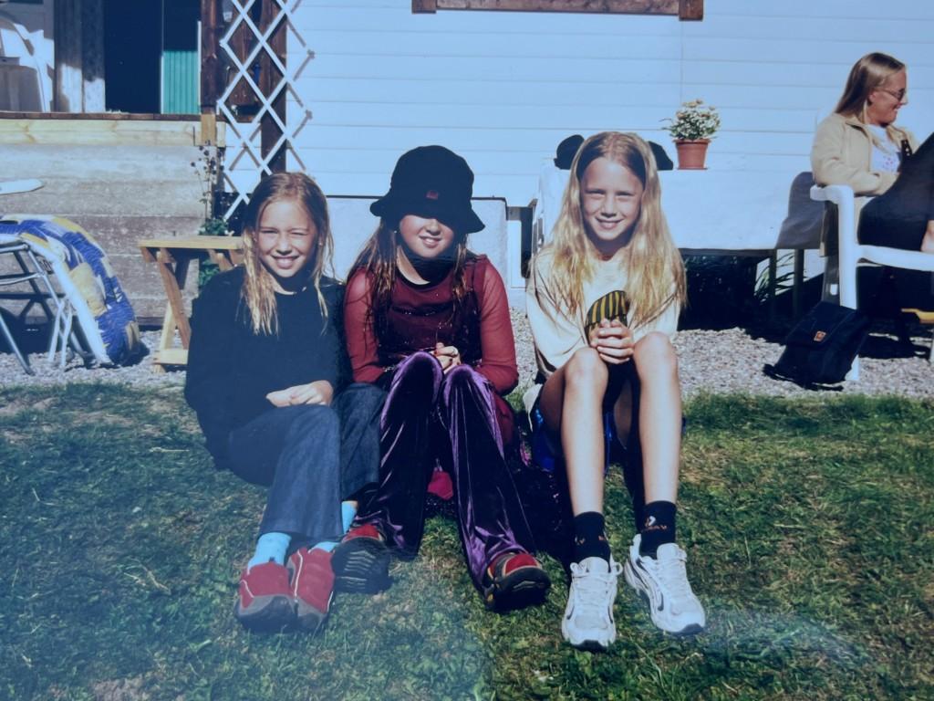 Tre yngre deltagare sitter framför huset på Harholmen
