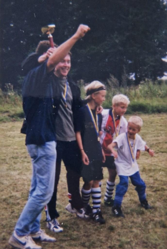 Ett lag firar med medaljer och pokal på fotbollsplanen