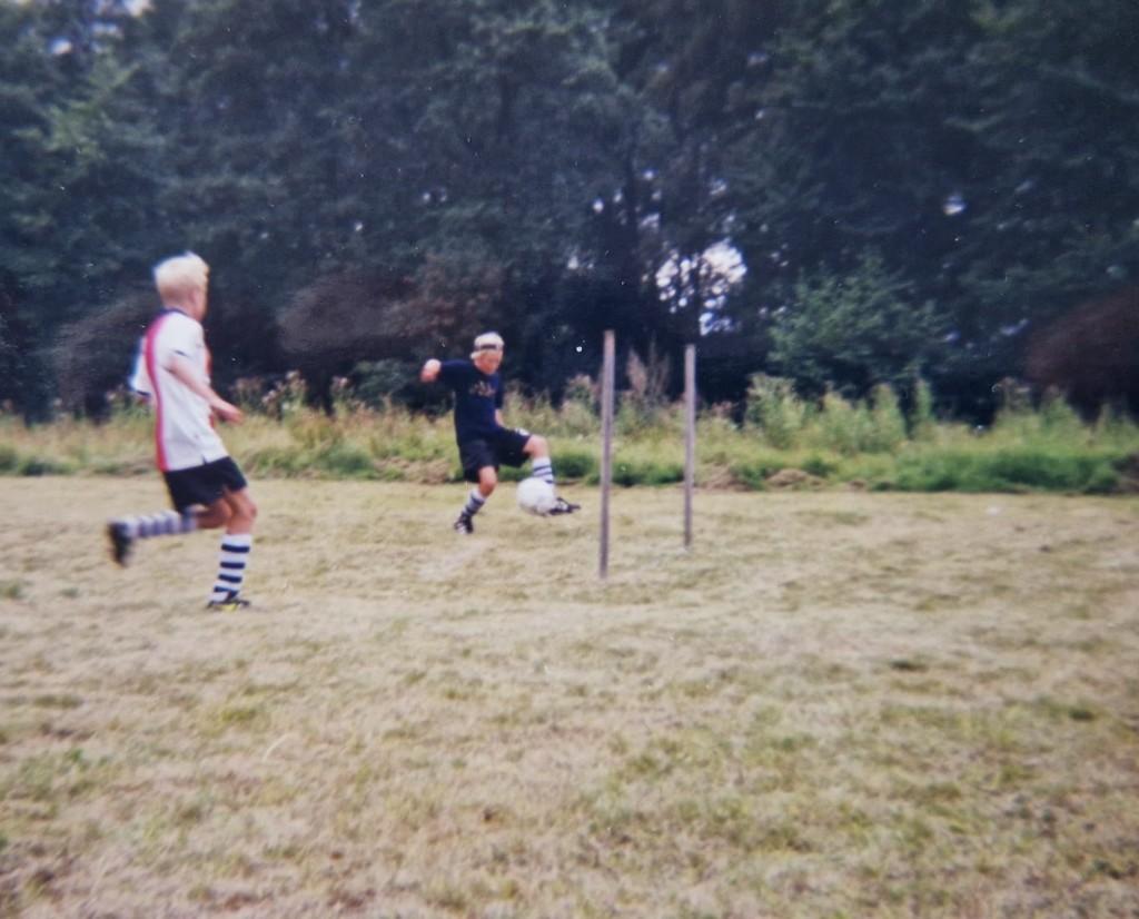 Två barn spelar fotboll mellan enkla stolpmål